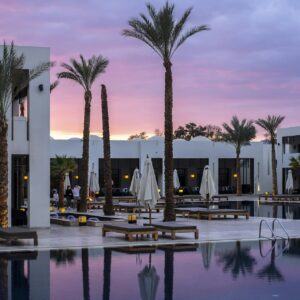 Palm-lined pool of the Demo Grand Hotel & Spa Aqaba at sunset