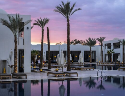 Palm-lined pool of the Demo Grand Hotel & Spa Aqaba at sunset